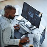 Man at a desk working with two computers in regulated industries