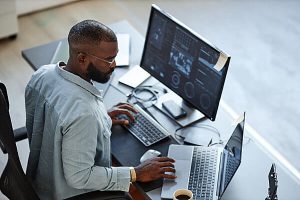 Man at a desk working with two computers in regulated industries