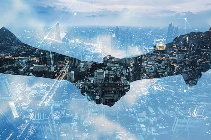 Two business people shaking hands in front of a window overlooking a city representing FluentStream's Cloud Phone System Partner Program .