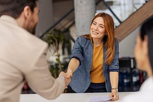 A woman working with legal firms shaking hands with a man in a suit