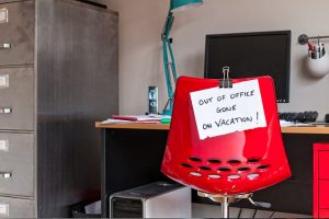 Temporary voicemail greeting options for office worker with an out of office for vacation sign on the back of their red desk chair