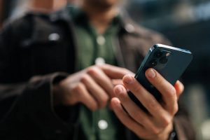 Close up of man's hands using cloud-based phone systems for small business on his mobile phone