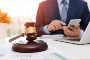 Lawyer at his desk, with a gavel in the foreground, using VoIP for legal firms on his mobile phone