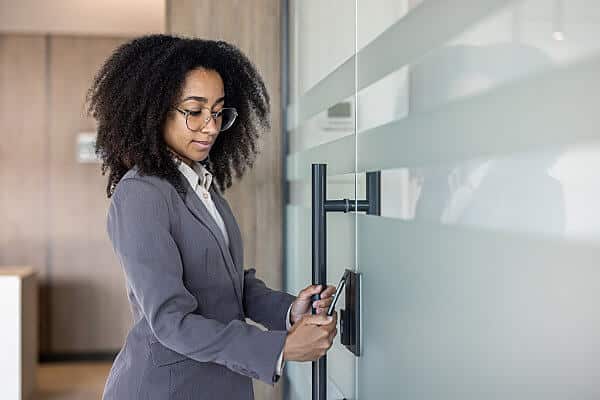 Young woman using a card key to get through a secure building's door. A POTS line replacement solution, like AirDial by FluentStream, keeps this security feature connected.