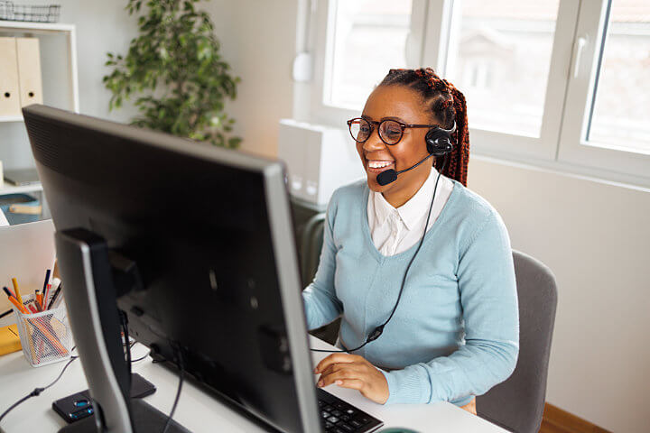 Woman on a headset working on her remote job in her home office